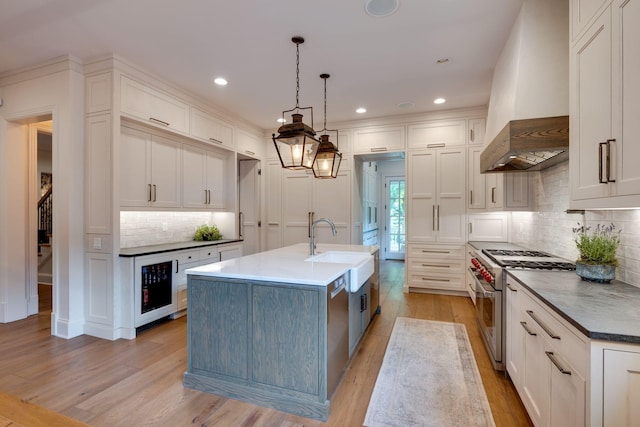 622 Stonewater Blvd, Franklin, TN 37064 - kitchen featuring stainless steel range, wall chimney range hood, beverage cooler, light wood-style floors, and a sink