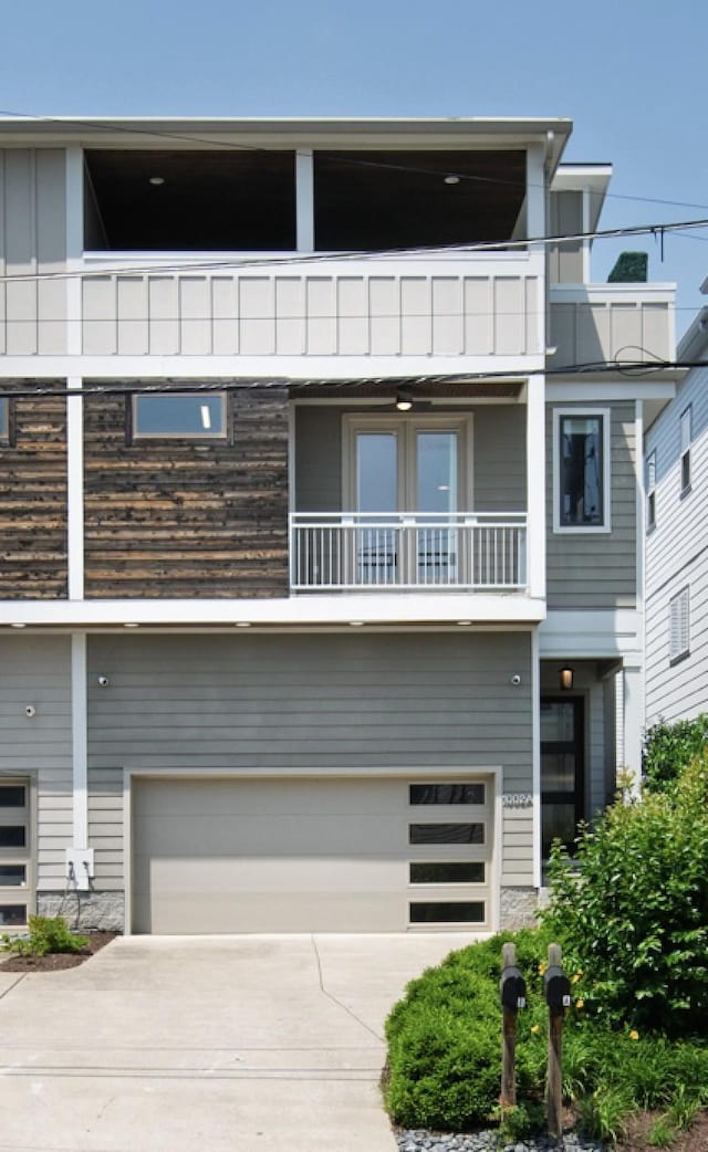 view of front of home with a balcony, an attached garage, concrete driveway, and board and batten siding