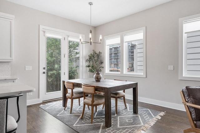 dining room with a chandelier, dark wood finished floors, and baseboards