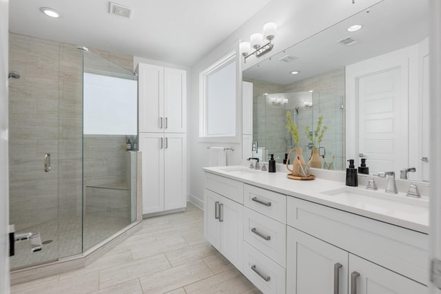 bathroom featuring a shower stall, double vanity, and recessed lighting