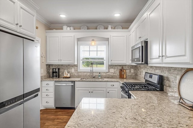 401 Hancock Ln, Tullahoma, TN 37388 - kitchen with stainless steel appliances, a sink, white cabinets, decorative backsplash, and crown molding