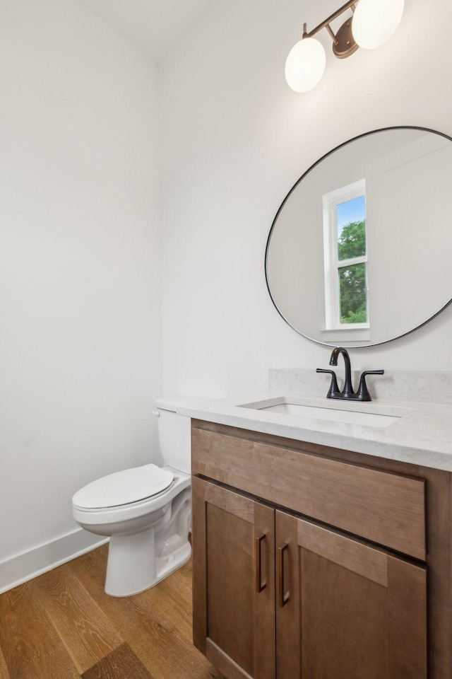 bathroom with wood finished floors, toilet, and vanity