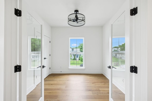 entryway with french doors, light wood finished floors, and baseboards