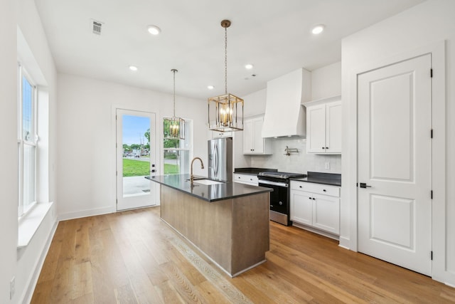 kitchen featuring appliances with stainless steel finishes, dark countertops, custom range hood, decorative backsplash, and a chandelier