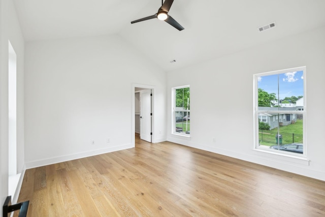 spare room with healthy amount of natural light, ceiling fan, light wood-type flooring, baseboards, and high vaulted ceiling