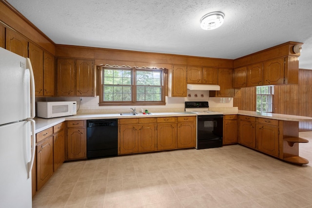 915 Taylor Cir, Burns, TN 37029 - kitchen featuring white appliances, under cabinet range hood, a sink, brown cabinetry, and a peninsula