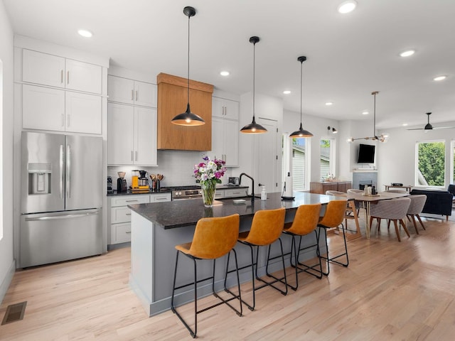 1319 Monetta Ave, Nashville, TN 37216 - kitchen with appliances with stainless steel finishes, a kitchen island with sink, light wood-style floors, a breakfast bar area, and recessed lighting