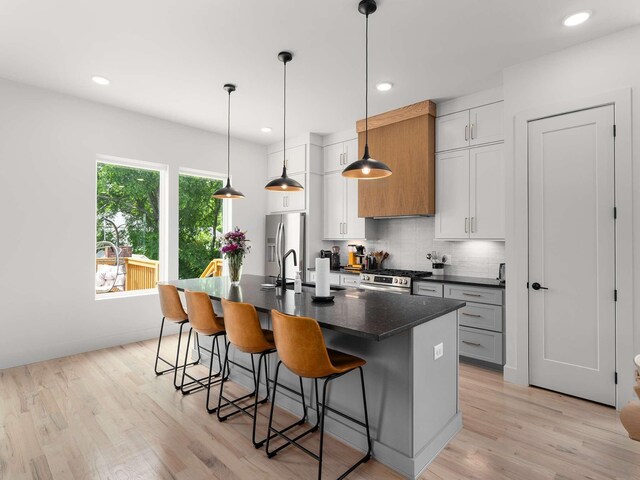 1319 Monetta Ave, Nashville, TN 37216 - kitchen featuring dark countertops, appliances with stainless steel finishes, a kitchen bar, an island with sink, and decorative backsplash