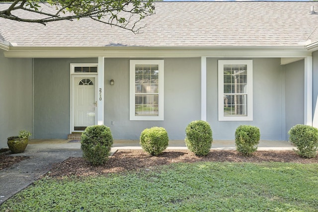 view of exterior entry featuring roof with shingles and covered porch