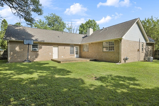 back of house with a chimney, brick siding, a lawn, and roof with shingles