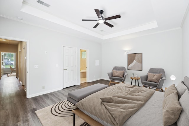 bedroom with a raised ceiling, dark wood-style floors, crown molding, and baseboards