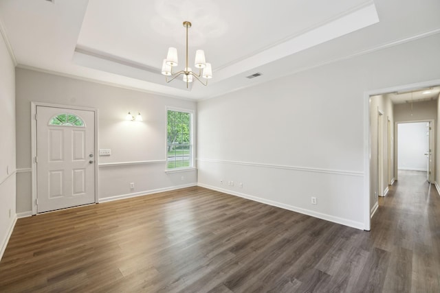 unfurnished room featuring a tray ceiling, a chandelier, wood finished floors, baseboards, and ornamental molding