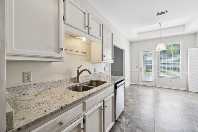 kitchen featuring a sink, dishwasher, a tray ceiling, baseboards, and pendant lighting
