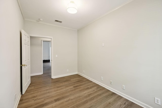 unfurnished room with crown molding, wood finished floors, and baseboards