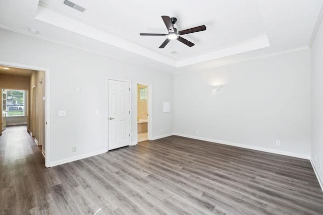 unfurnished bedroom with a tray ceiling, crown molding, wood finished floors, baseboards, and ceiling fan