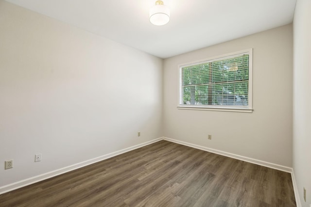 spare room featuring dark wood-style flooring and baseboards