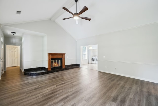 unfurnished living room with washing machine and clothes dryer, ceiling fan, beamed ceiling, wood finished floors, and a glass covered fireplace