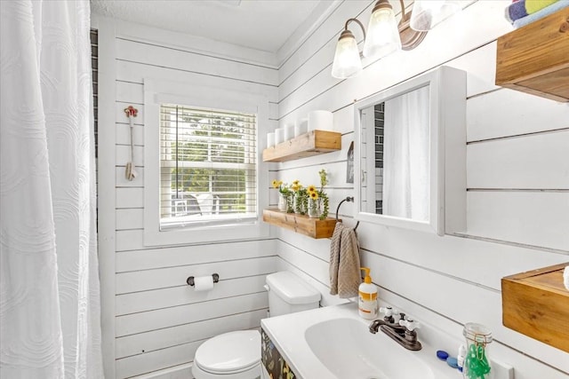 bathroom with toilet, vanity, wood walls, and curtained shower
