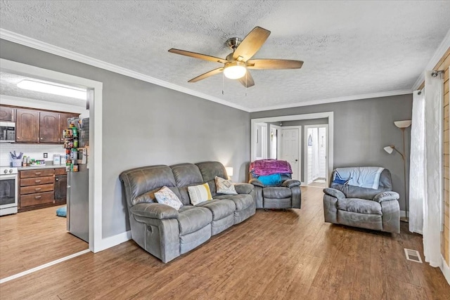 living area featuring light wood-type flooring, a textured ceiling, a ceiling fan, and baseboards