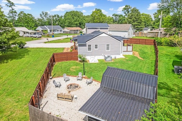 back of house with cooling unit, an outdoor fire pit, a residential view, and metal roof