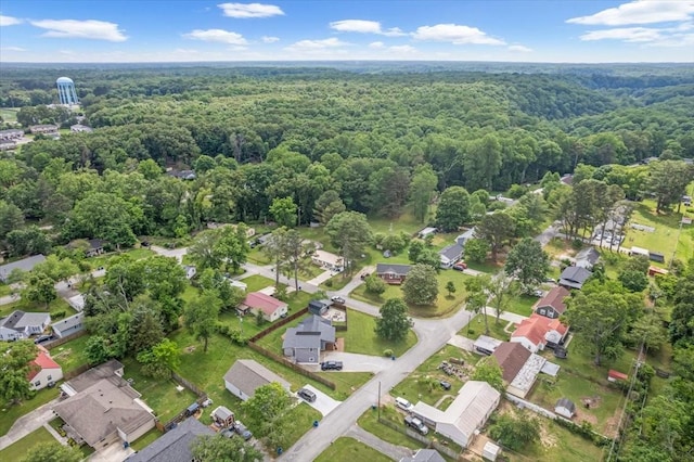 aerial view of property's location featuring a forest and nearby suburban area