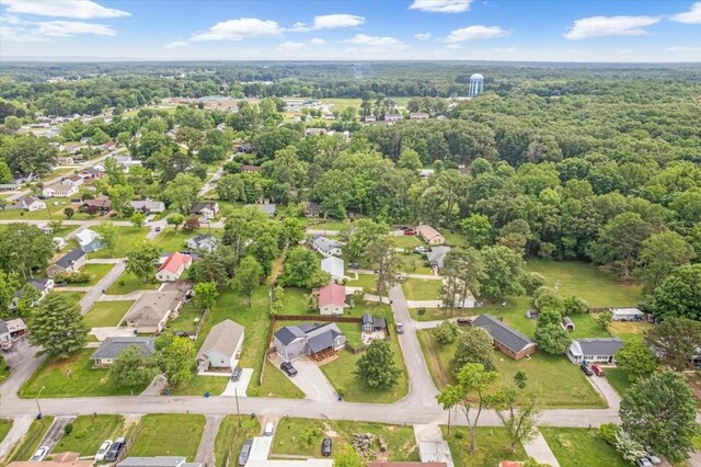 aerial view of property and surrounding area featuring nearby suburban area and a forest