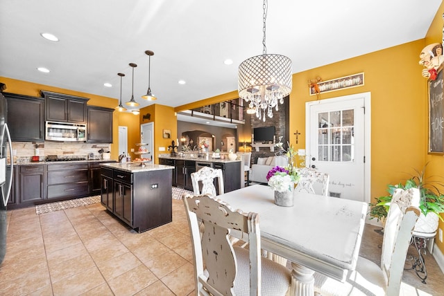 3015 Prince Dr, Clarksville, TN 37043 - kitchen featuring appliances with stainless steel finishes, an island with sink, decorative backsplash, dark brown cabinetry, and a chandelier