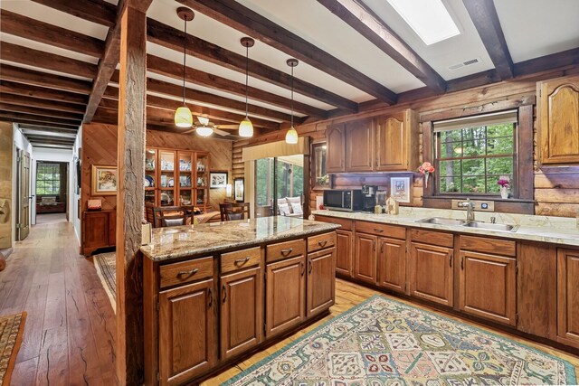 7261 Kingston Rd, Fairview, TN 37062 - kitchen with a sink, stainless steel microwave, wood walls, beamed ceiling, and brown cabinetry