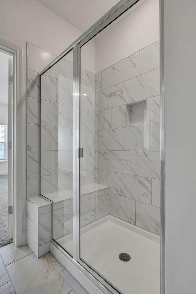 bathroom with a stall shower and marble finish flooring