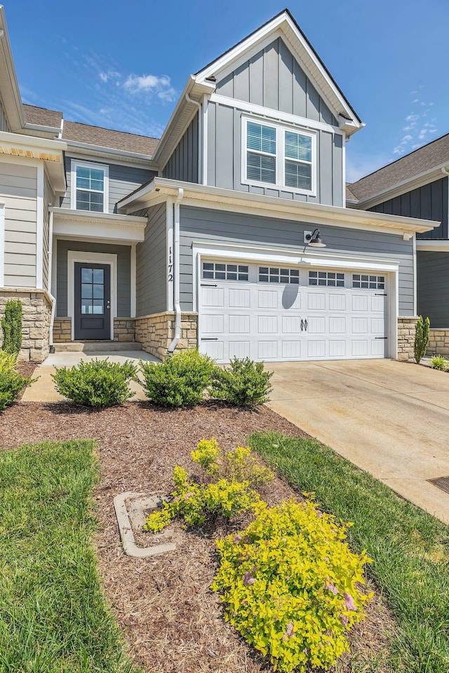 craftsman-style home with board and batten siding, stone siding, driveway, and an attached garage