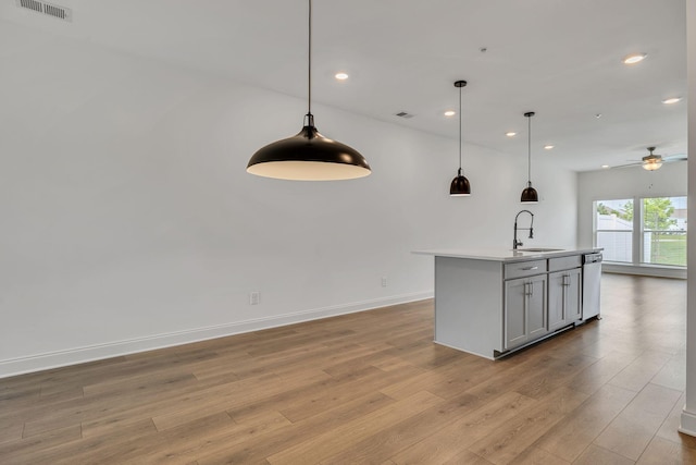 kitchen featuring dishwasher, a sink, open floor plan, recessed lighting, and light wood finished floors
