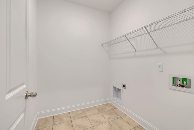 clothes washing area with electric dryer hookup, washer hookup, baseboards, and light tile patterned flooring
