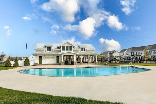 community pool featuring a patio area, fence, and a residential view