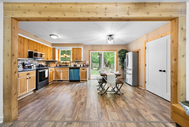 kitchen with stainless steel appliances, dark countertops, dark wood-style flooring, and a sink