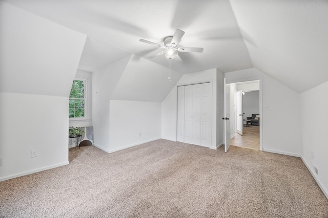 additional living space featuring light colored carpet, vaulted ceiling, a ceiling fan, and baseboards