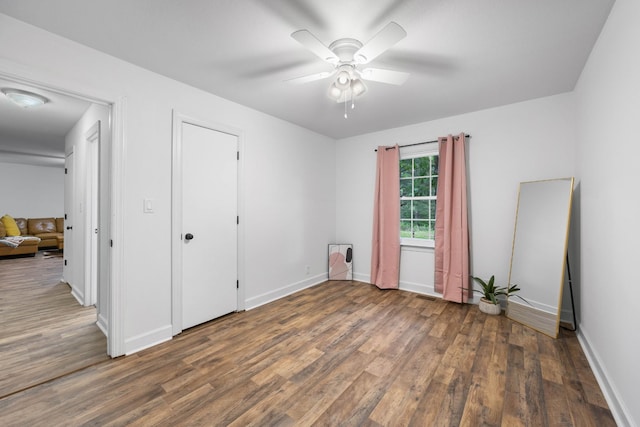 unfurnished bedroom featuring wood finished floors, baseboards, and a ceiling fan