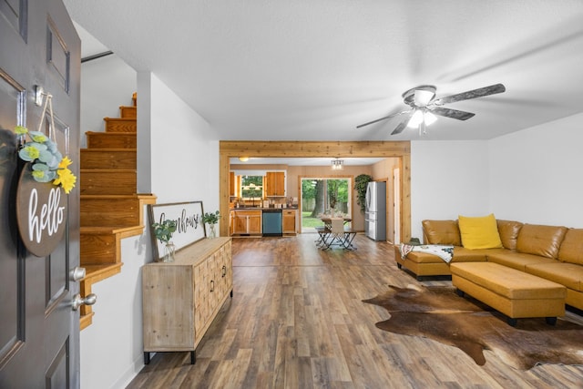 living room with dark wood-type flooring, a ceiling fan, and stairs