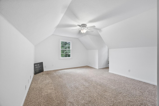 bonus room with carpet floors, ceiling fan, vaulted ceiling, baseboards, and a textured ceiling