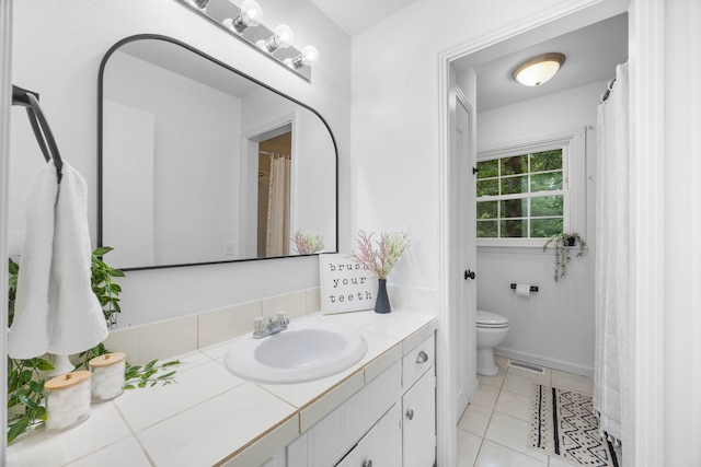 bathroom with toilet, vanity, and tile patterned flooring