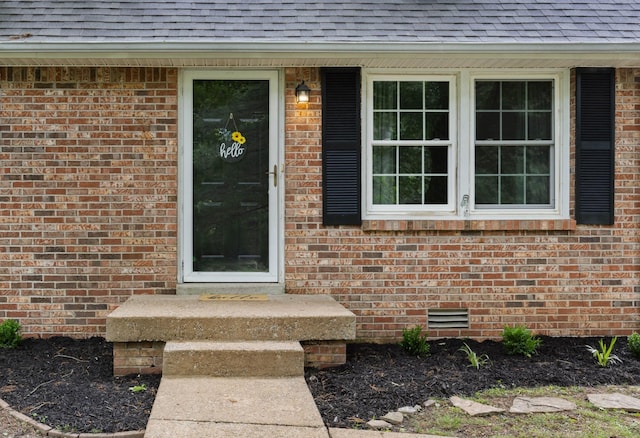 property entrance featuring a shingled roof, brick siding, and crawl space