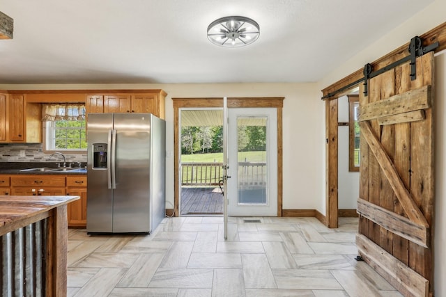 46 Seay Ln, Erin, TN 37061 - kitchen featuring stainless steel fridge, a sink, a barn door, dark countertops, and brown cabinetry