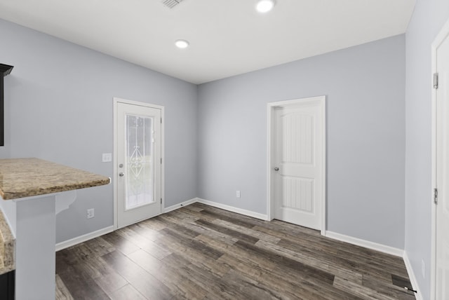 unfurnished dining area featuring dark wood-style flooring, baseboards, and recessed lighting