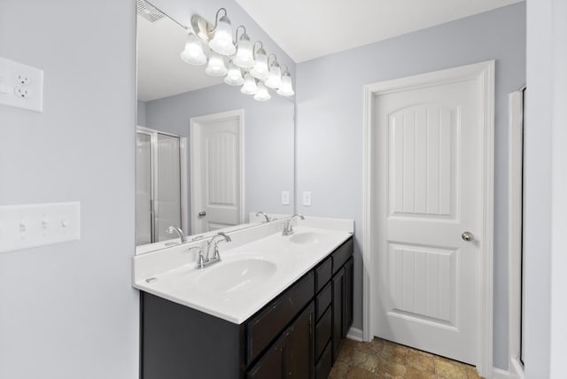 full bath featuring double vanity, a shower with shower door, stone finish flooring, and baseboards