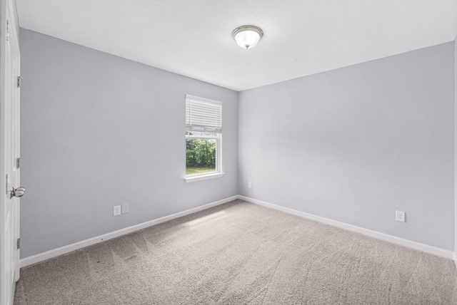 carpeted empty room featuring baseboards