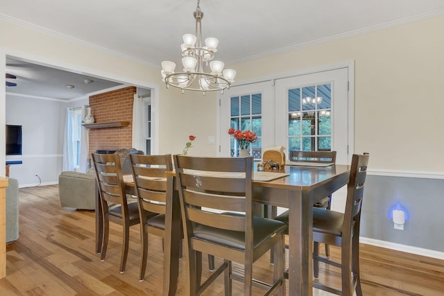 1186 Peebles Dr, Smyrna, TN 37167 - dining space featuring a chandelier, baseboards, wood finished floors, crown molding, and a brick fireplace
