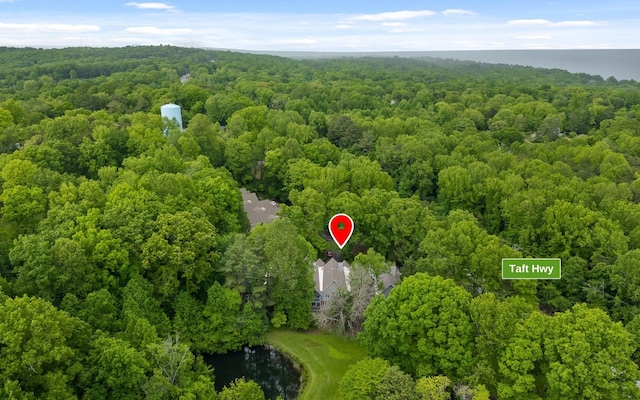 aerial view of property and surrounding area with a heavily wooded area and a nearby body of water