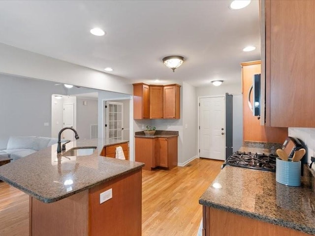 3904 Rowland Rd, Murfreesboro, TN 37128 - kitchen featuring a sink, brown cabinets, stainless steel microwave, light wood-style flooring, and an island with sink