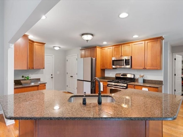 3904 Rowland Rd, Murfreesboro, TN 37128 - kitchen featuring stainless steel appliances, a sink, dark stone counters, light wood finished floors, and a kitchen island with sink