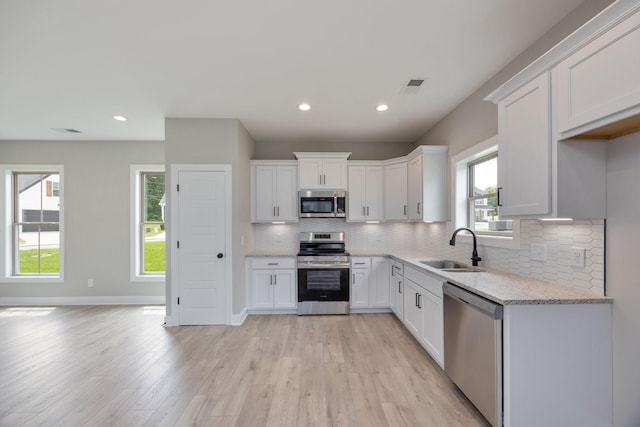 2050 Rylee Way, Greenbrier, TN 37073 - kitchen featuring appliances with stainless steel finishes, a sink, white cabinets, backsplash, and light wood finished floors