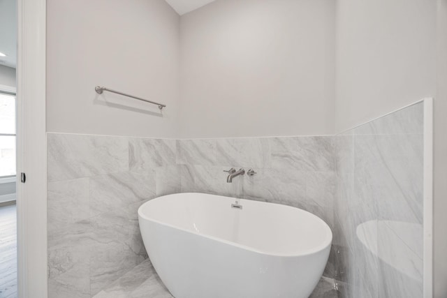 2050 Rylee Way, Greenbrier, TN 37073 - bathroom featuring tile walls, a freestanding bath, marble finish flooring, and wainscoting
